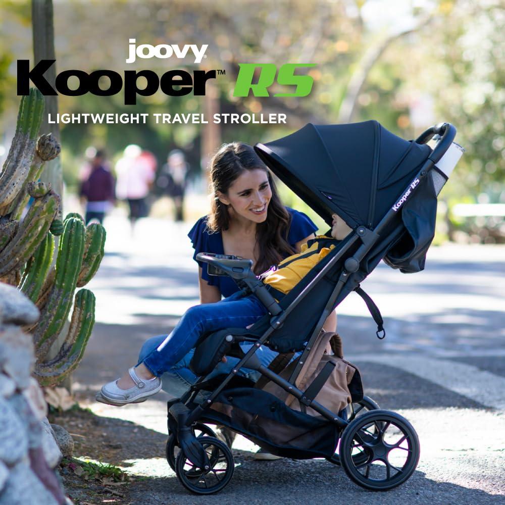 imageJoovy Kooper Lightweight Baby Stroller Featuring Removable SwingOpen Tray Big Wheels Reclining Seat with Footrest ExtraLarge Retractable Canopy and Compact Fold SandBlack